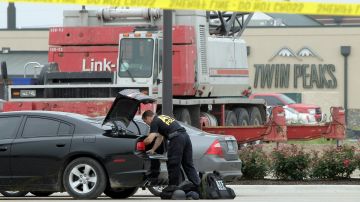 La Policía en Waco, Texas, recoje evidencias de veh'iculos estacionados en el restaurante donde se enfrentaron dos pandillas de moticiclistas el domingo pasado.