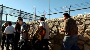 Inmigrantes deportados cruzan la frontera hacia México.
