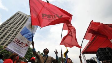 Seguidores del presidente venezolano, Hugo Chávez, ondean banderas rojas horas antes de la inauguración de la primera Cumbre de la Comunidad de Estados de América Latina y el Caribe (CELAC).