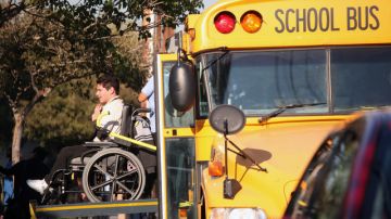 Un estudiante en silla de ruedas es auxiliado a descender de un autobús escolar de la secundaria Santee en Los Ángeles.