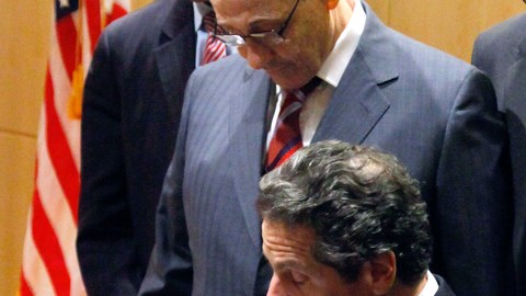 El gobernador Andrew Cuomo (sentado), estampa su firma en una medida que crearía un programa de  empleos a los jóvenes de centros urbanos. Le acompañaron en la ceremonia varios líderes estatales de NY.