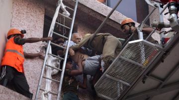 Trabajadores de los equipos de rescate evacúan el cuerpo sin vida de una paciente del hospital de AMRI en Calcuta.