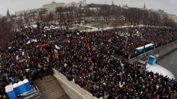 Manifestantes se reúnen para protestar cerca del Kremlin, al fondo, contra el presunto fraude electoral en las elecciones parlamentarias de Rusia en Moscú.