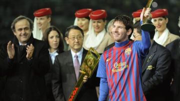 Lionel Messi  levanta el trofeo del Balón de Oro en presencia del presidente de Toyota, Akio Toyoda (centro, que sostiene la "llave" que también le fue entregada a Messi de jugador más valioso del torneo) y del presidente de la UEFA, Michel Platini (izq.), después   que   Barcelona derrotara al Santos   en la final del Mundial de Clubes disputada en Tokio.