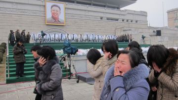 Simpatizantes lloran la muerte del líder coreano, Kin Jong-il, al pasar frente a su retrato en la plaza de los Estudiantes.