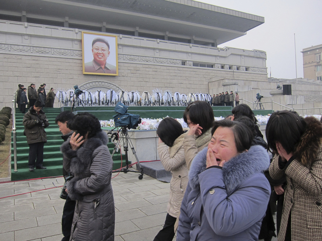 Simpatizantes lloran la muerte del líder coreano, Kin Jong-il, al pasar frente a su retrato en la plaza de los Estudiantes.