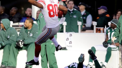 Víctor Cruz salta sobre un defensa de los Jets para anotar un  touchdown de 99 yardas durante el segundo cuarto que hizo aumentar la ventaja de los Giants.