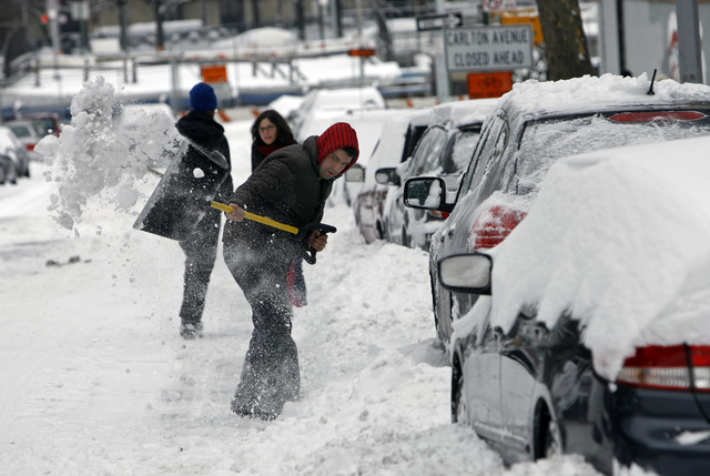 Un hombre trata de sacar su auto que quedó enterrado por la nieve en Brooklyn.
