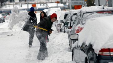 Un hombre trata de sacar su auto que quedó enterrado por la nieve en Brooklyn.