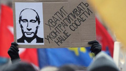 Manifestantes porta un cartel contra el primer ministro ruso, Vladimir Putin, durante la multitudinaria protesta celebrada en Moscú (Rusia).