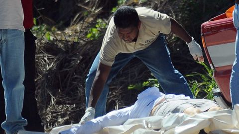 Empleados de medicina forense mientras realizan el levantamiento del cuerpo de la periodista Luz Marina Paz, asesinada en Tegucigalpa.