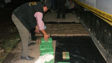 Agentes de la policía enfilan  los 113 kilos de cocaína decomisados dentro de un tráiler que fue detenido en una carretera del suroeste del país y que era conducido hacia territorio mexicano.