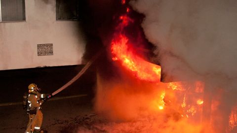 Un bombero de Los Angeles extingue uno de los recientes incendios que alcanzó a varios carros en el vecindario de Sun Valley.