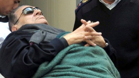 El expresidente egipcio Hosni Mubarak (c) abandona en camilla la sala tras asistir a una nueva sesión de su juicio celebrado en la Academia de Policía.