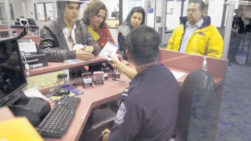 Extranjeros que ingresan con visas de turista al aeropuerto de las Vegas muestran sus documentos al personal de aduana.