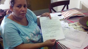 La dominicana María Pabón dice que le pagó a una compatriota que trabajaba en bienes raíces unos $5,000 para que le consiguiera un apartamento. En la foto, Pabón muestra copia del supuesto contrato falso de arrendamiento que recibió.