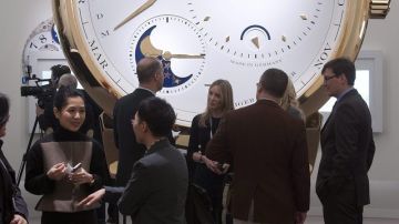 Periodistas conversan ante una maqueta de un reloj de la firma "Lange and Soehne".