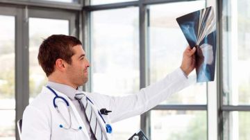 Un médico examina radiografías realizadas a un paciente con cáncer de próstata.