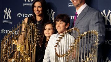 Jorge Posada (der.), posa con su esposa, Laura Posada, rodeado de los trofeos de Series Mundiales y sus hijos, Paulina Posada y Jorge Posada Jr., mientras se despedía del béisbol, ayer en el Yankee Stadium.