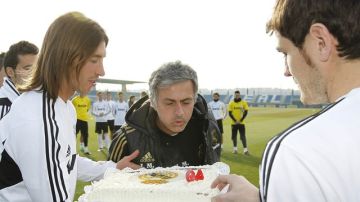 El entrenador de Real Madrid José Mourinho (centro) sopla las velas del bizcocho que le presentaron ayer Sergio Ramos (izq.) e Iker Casillas (der.) en su 49no.  cumpleaños.