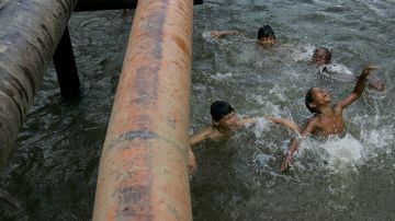 En foto de archivo, niños  juegan en un río donde las tuberías de petróleo corren por encima de la superficie en la provincia de Sucumbíos en Ecuador.
