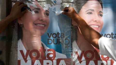 Un hombre rasga una publicidad política de la candidata presidencial venezolana María Corina Machado ayer en una calle de Caracas.