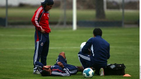 Alberto Medina es atendido por el médico de cancha, Narciso López, luego de ser golpeado en el tobillo derecho en el entrenamiento de ayer.