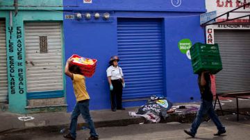 Personas pasan junto al  cadáver de Alberto Archila, asesinado el viernes, en la calle en Ciudad de Guatemala, mientras se cumple la diligencia judicial respectiva.