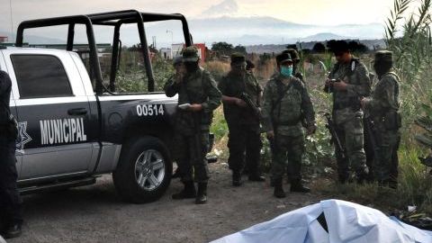 Oficiales investigan la escena del hallazgo de los cuerpos.