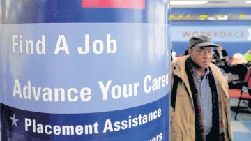 Un hombre pasa al lado de un cartel en el que se detallan los servicios que presta el centro de desempleo (Workforce1 Career Center) en Brooklyn.