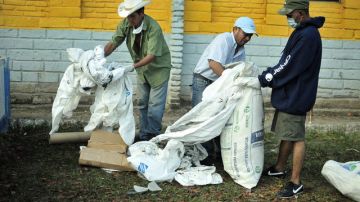 Reos limpian la zona donde fueron colocados los cuerpos de sus compañeros muertos en el incendio en la Granja Penal de Comayagua.
