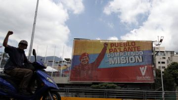 Un motociclista pasa frente a una valla con la imagen del presidente venezolano Hugo Chávez cuando faltan pocos meses  para las elecciones presidenciales.