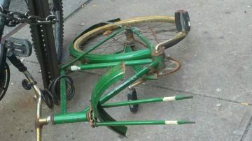 Una bicicleta inservible es dejada en la vereda y asegurada a un poste vial.