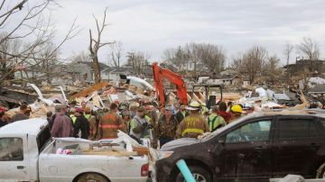 Socorristas ayudan a limpiar los escombros dejados por  el paso del tornado en el vecindario de Harrisburg, en Ilinois.