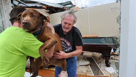 Un vecino presta ayuda a Greg Cook, quien acaba de salvar a su perrito de los escombros en que hoy quedó convertida su residencia en Alabama.