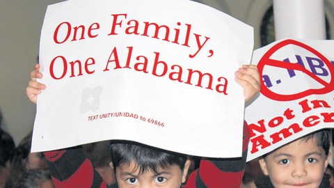 Dos niños sostienen unos carteles durante un mitín el  lunes 21 de noviembre de 2011, en Birmingham, Alabama,  para exigir la revocación de la ley HB56 que criminaliza a los inmigrantes indocumentados en Alabama.