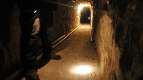 Un policía mexicano enciende su linterna para mostrar el interior de este túnel que tiene 3798 pies de largo que pasa de México a EE.UU. por el sur de California.