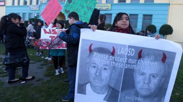 Una estudiante de la primaria Miramonte carga un cartel con las fotos de los dos maestros acusados de abuso sexual: Mark Berndt (izq.) y Martin Springer (der.) .