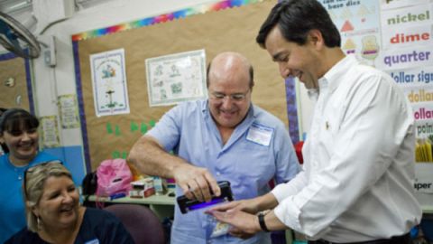 Un voluntario utiliza una luz para ver los dedos del Gobernador Fortuño (d), para confirmar que no ha votado anteriormente, el pasado 18 de marzo.
