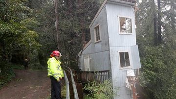 Los bomberos Greg Martin y Tim Williams estudian cómo ayudar en esta situación: Los fuertes vientos y la lluvia provocaron que esta casa se partiera en dos en Camp Meeker, en el condado de Sonoma, en California.