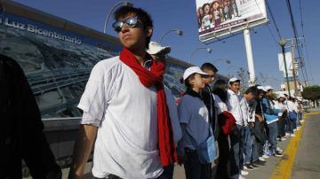 Jóvenes voluntarios hacen una calle de honor  a lo largo del camino que recorrió el papa Benedicto XVI a su llegada a León, estado de Guanajuato (México).  Arriba: la cadena humana esperó varias horas al Sumo Pontífice.