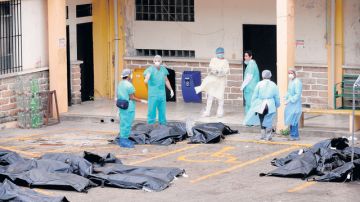 Médicos forenses practican el levantamiento de los cadáveres en el interior del penal de Comayagua, luego de un voraz incendio.