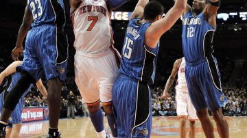 Carmelo Anthony, de los Knicks (con la bola), ataca hacia el canasto frente a la defensa de tres jugadores del Magic de  Orlando en el partido de anteanoche.