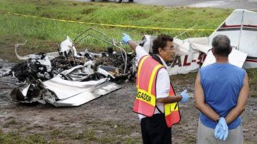 Dos investigadores observan  los restos de una avioneta que se estrelló ayer en el aeropuerto Marcos A. Gelabert, en Ciudad de Panamá.