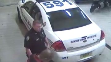 Zimmerman mira hacia abajo mientras habla con un policía.