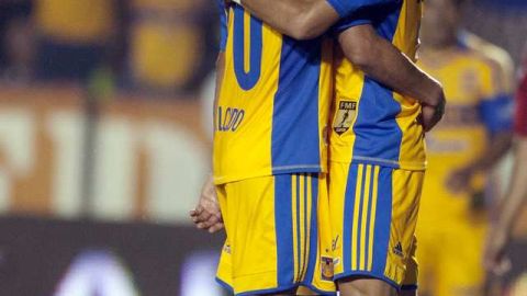 Carlos Salcido (izq.) y Alan Pulido se abrazan ante un jugador de Chivas, luego de su victoria.