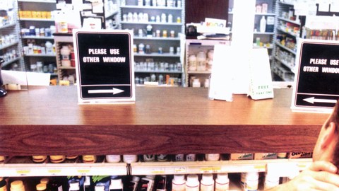 Un hombre frente al mostrador de una farmacia en Nueva York escoge una medicina para su compra.