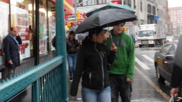 Una pareja, paraguas en mano, se protege  de la lluvia incesante que azotó ayer la ciudad, mientras camina  cerca a la calle Fulton, en el condado de Brooklyn.