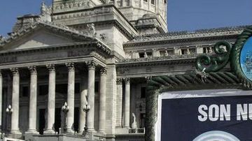 Un hombre pasa en bicicleta junto a un afiche de apoyo a la expropiación de la petrolera YPF  frente al Congreso Nacional en Buenos Aires (Argentina).