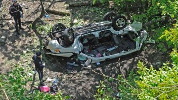 Policias investigan el van destruido después de haberse precipitado por un barranco, cuando venía por la Bronx River Parkway, ayer, en Nueva York.